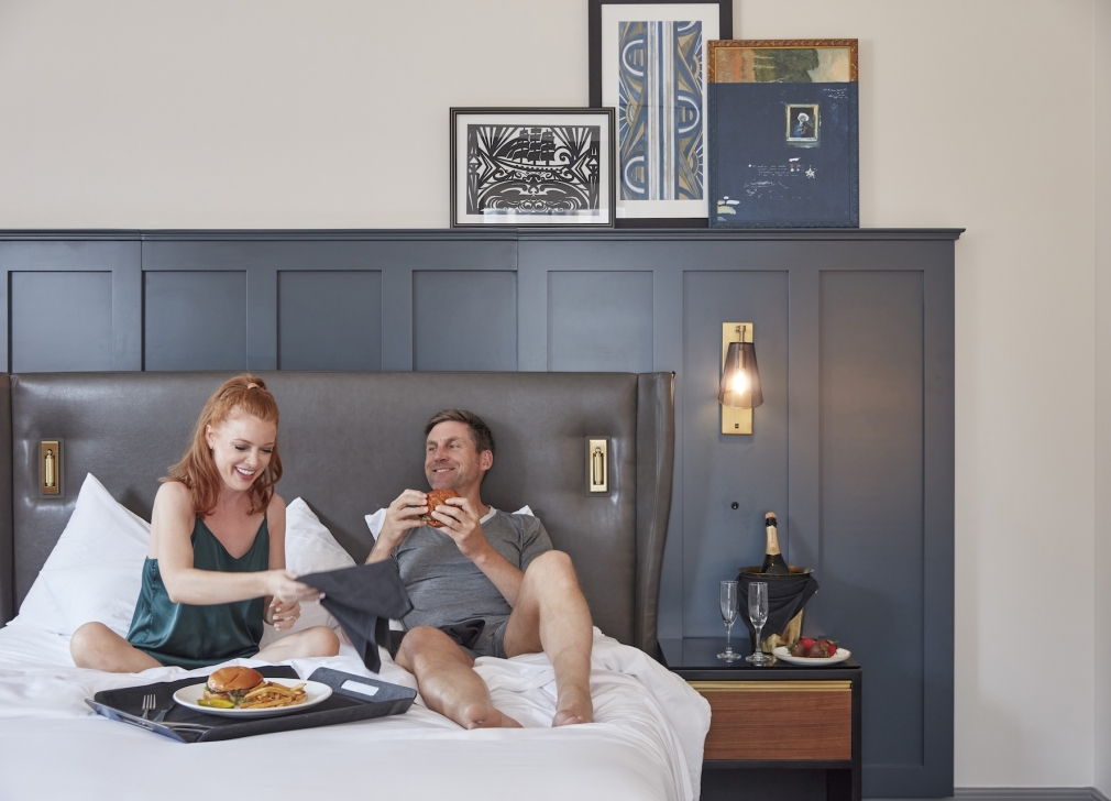 man and woman eating food on bed